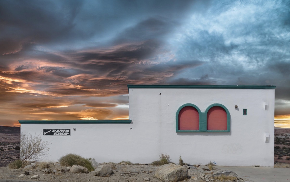 White building with two arched windows against a dramatic sunset sky with clouds.