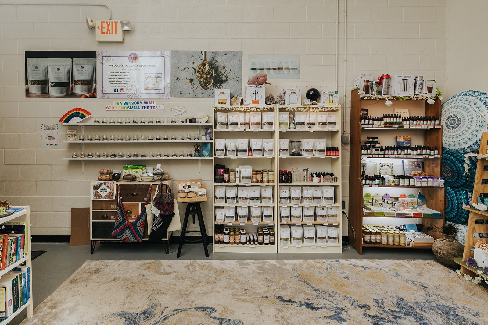Shelves with various products in a store, a table with items, and a patterned rug on the floor.