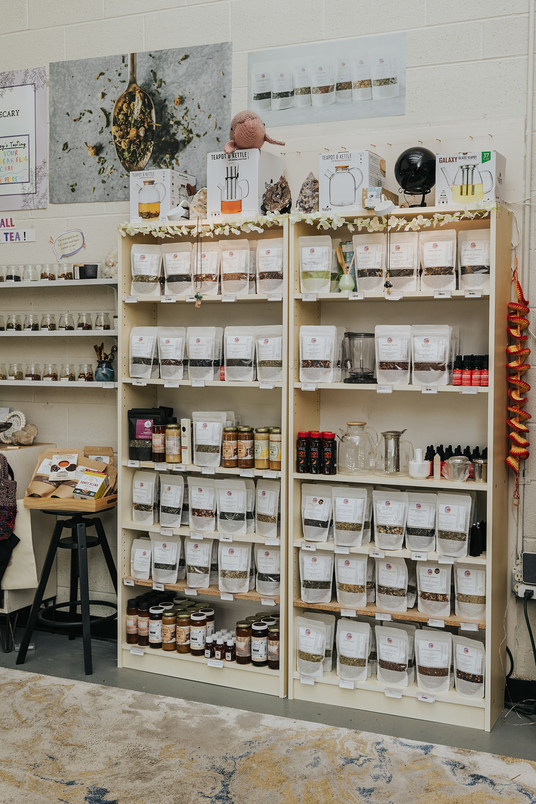 Two wooden shelves filled with jars and bottles in a store, with a person partially visible behind them.