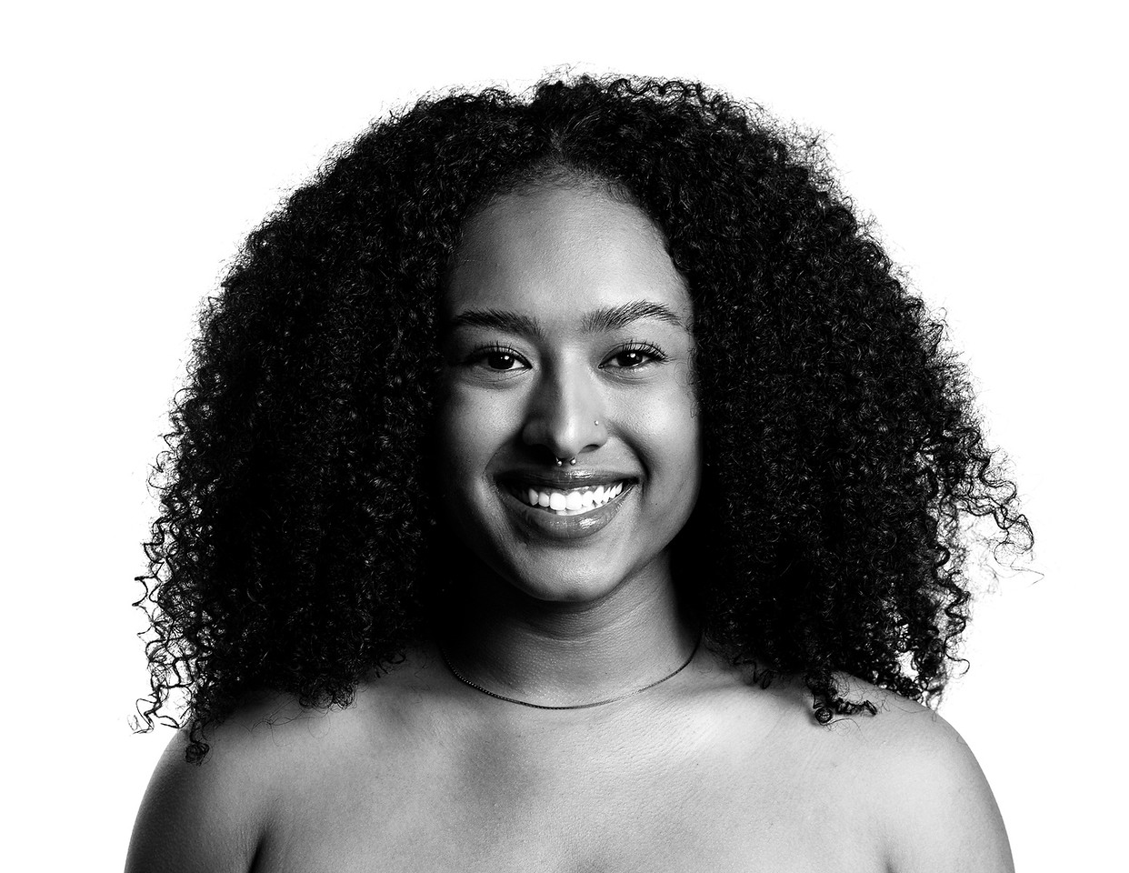 Smiling woman with curly hair facing forward, black and white photo.