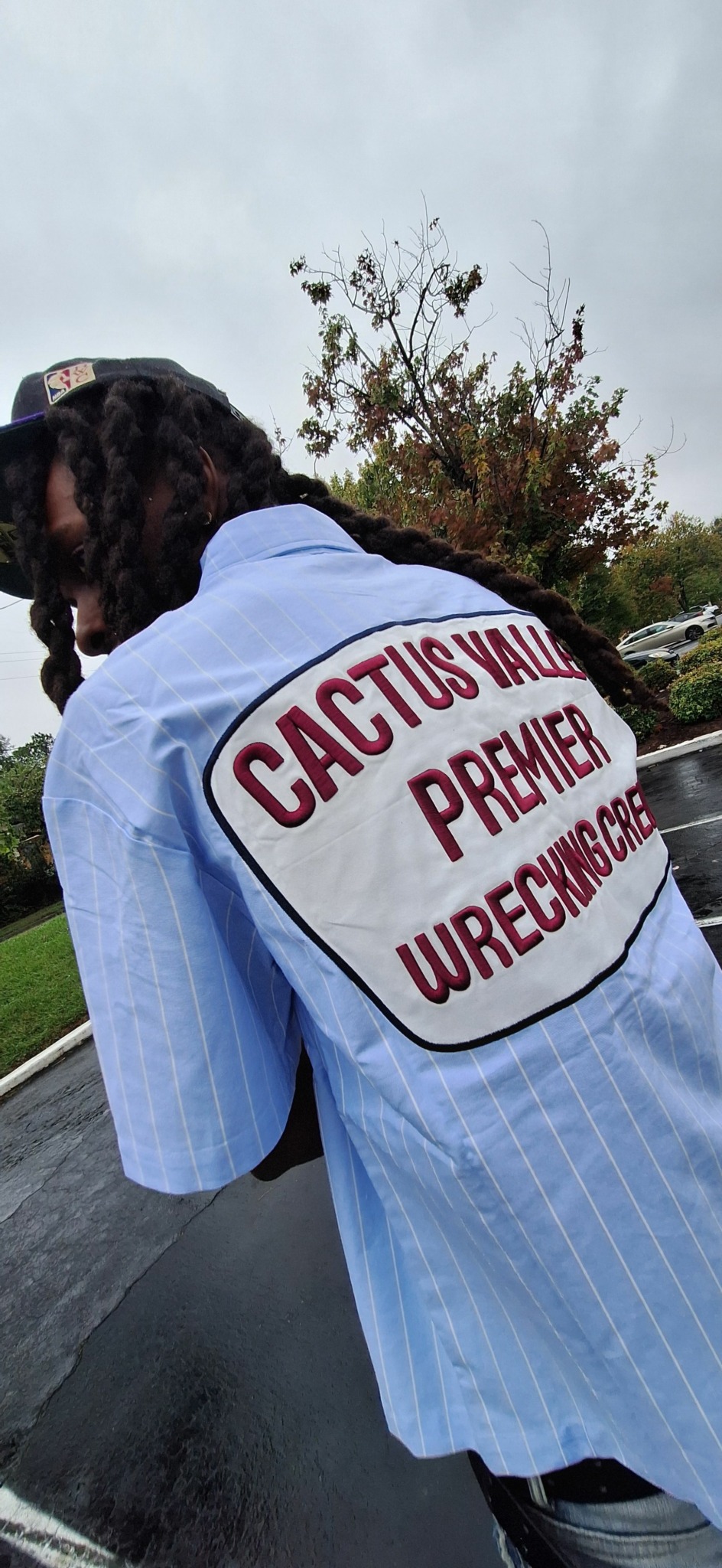 Person wearing a light blue shirt with a patch reading 'CASCIGU RECONSTRU' on the sleeve, outdoors.
