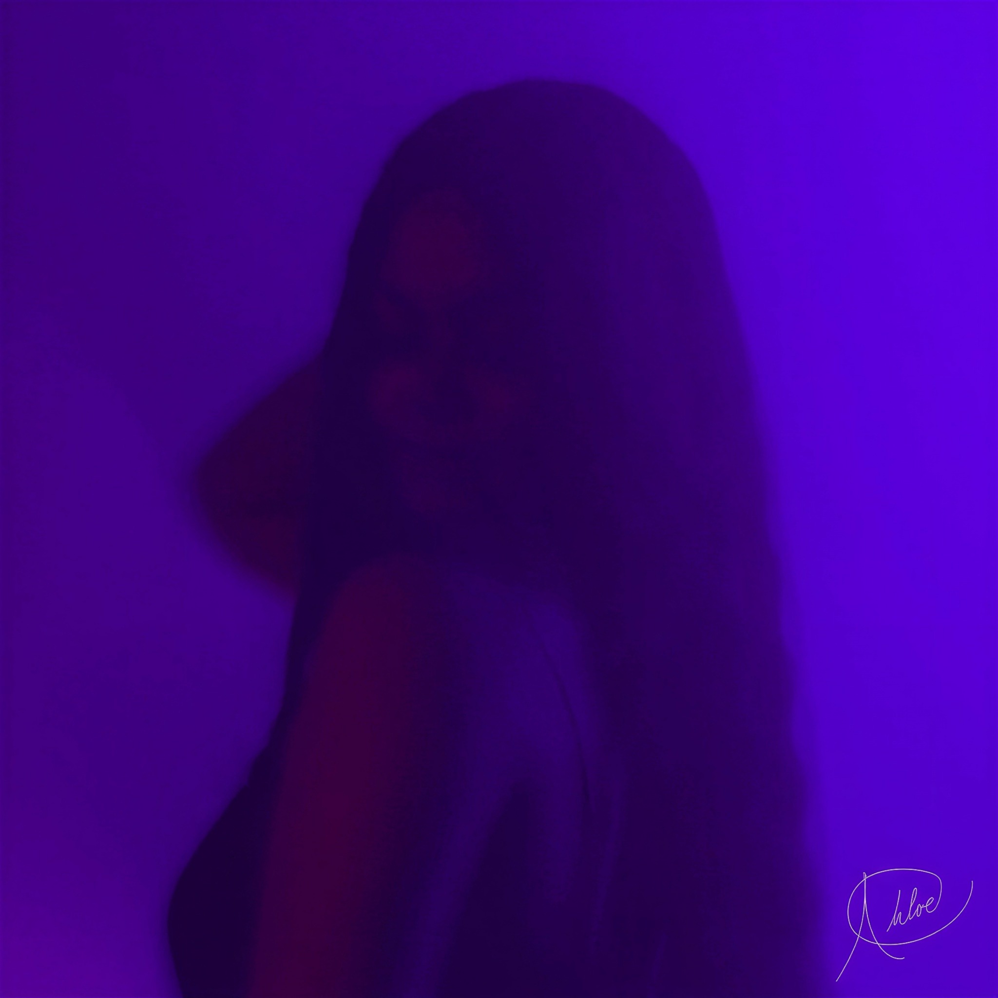 A person with long hair in a dark, purple-lit environment, facing slightly to the side, with a faint smile.