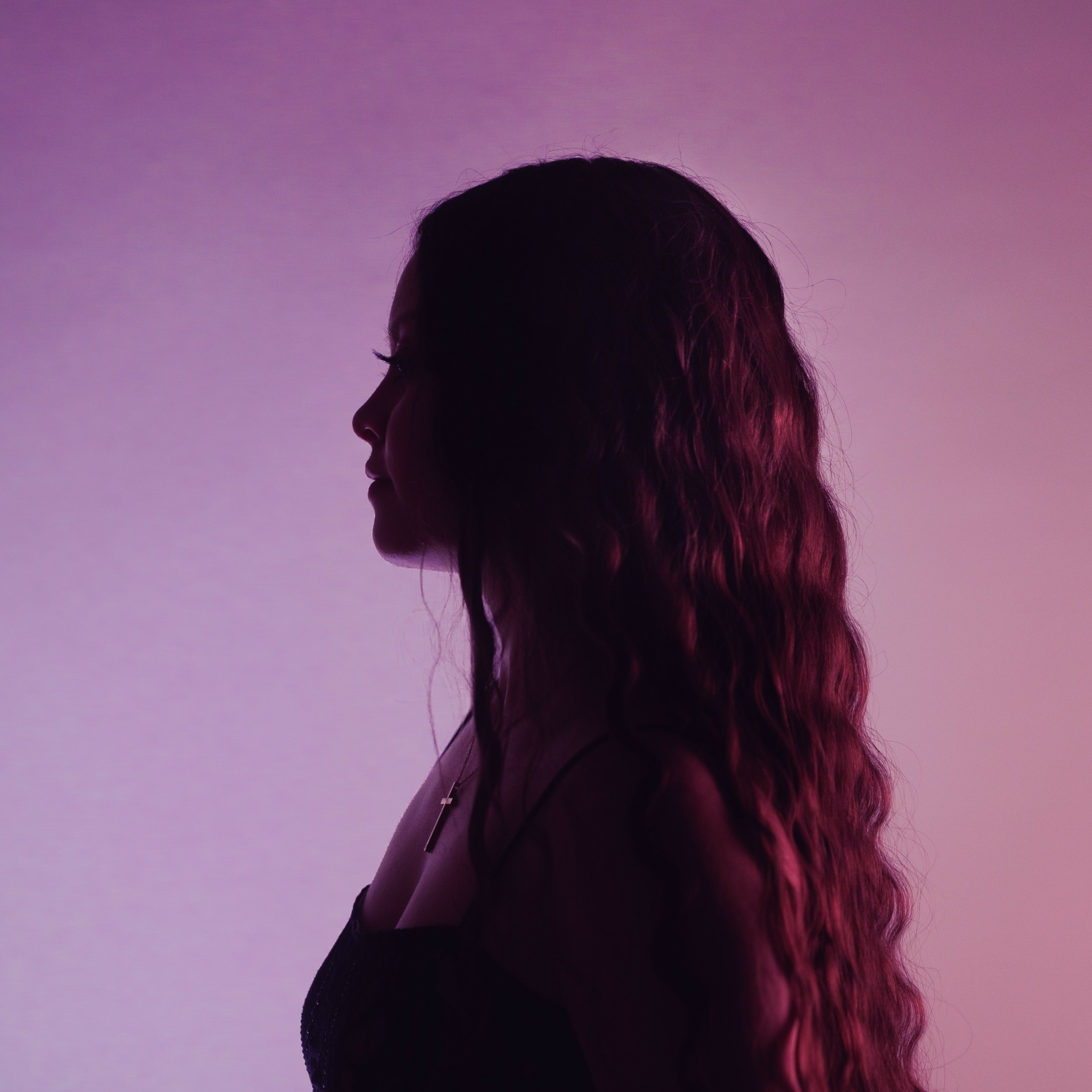 Silhouette of a woman with long wavy hair against a pink and purple gradient background.