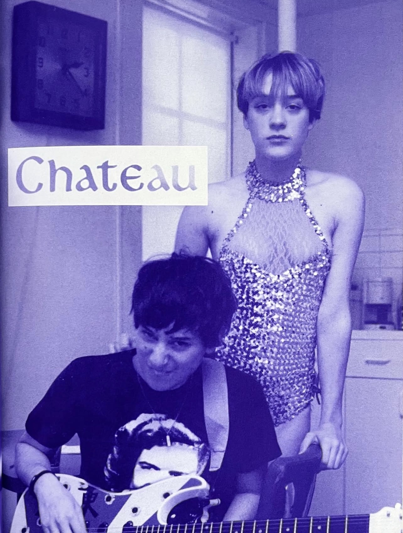 Two people, one standing and one sitting, in a room with a window and a clock, in black and white.