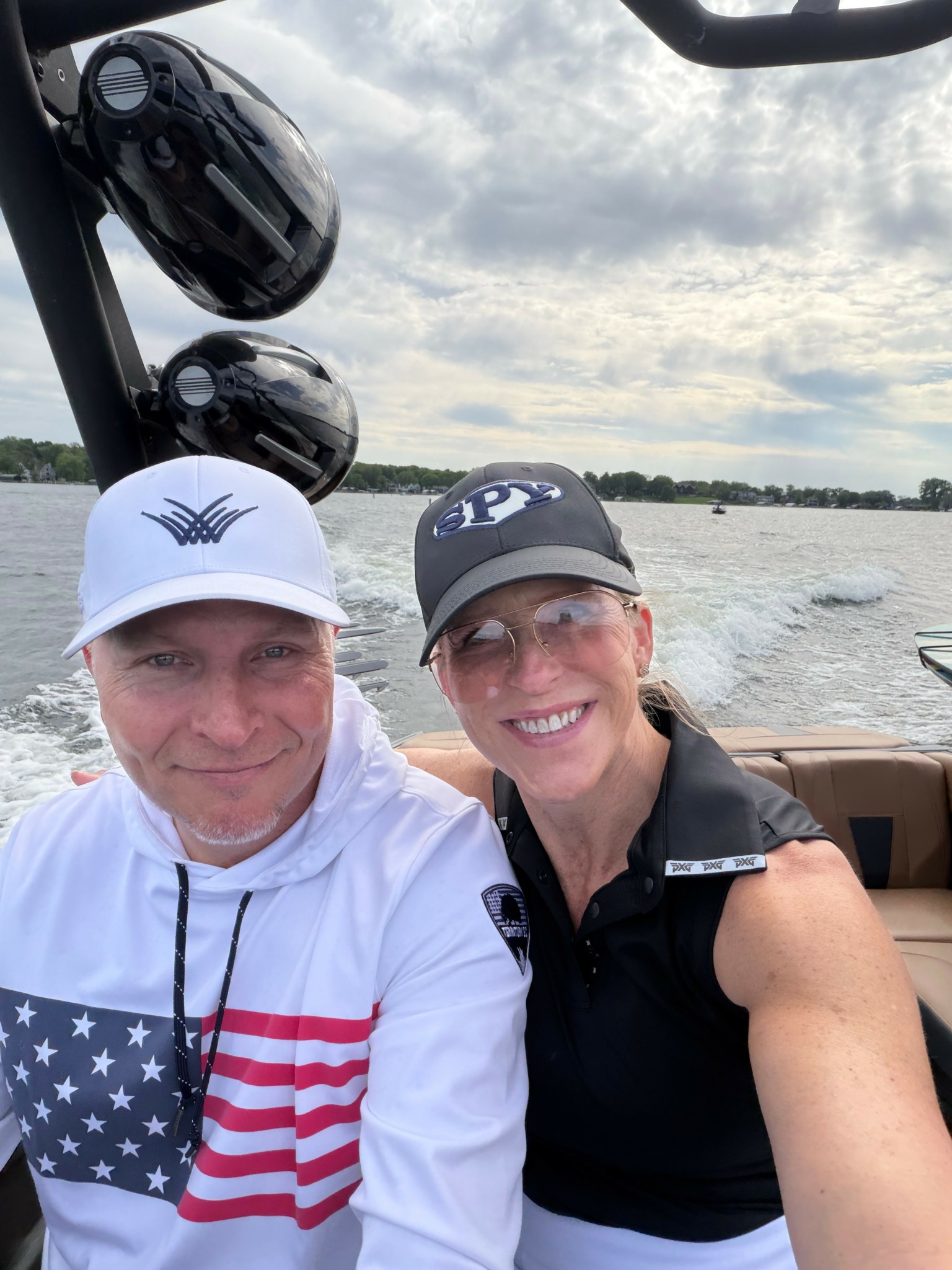 Two people smiling on a boat with water and sky in the background.