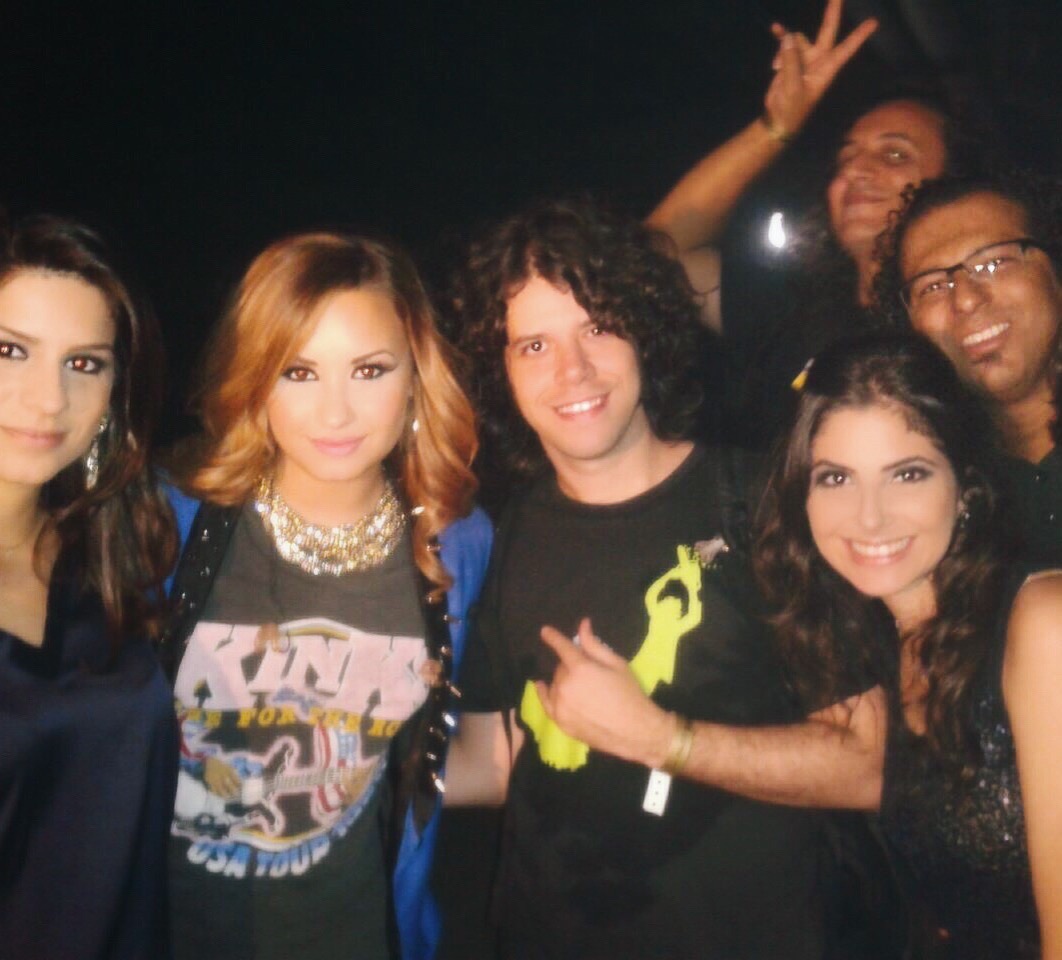 Group of six people smiling and posing together at a party or event, some making peace signs, in a dark background.