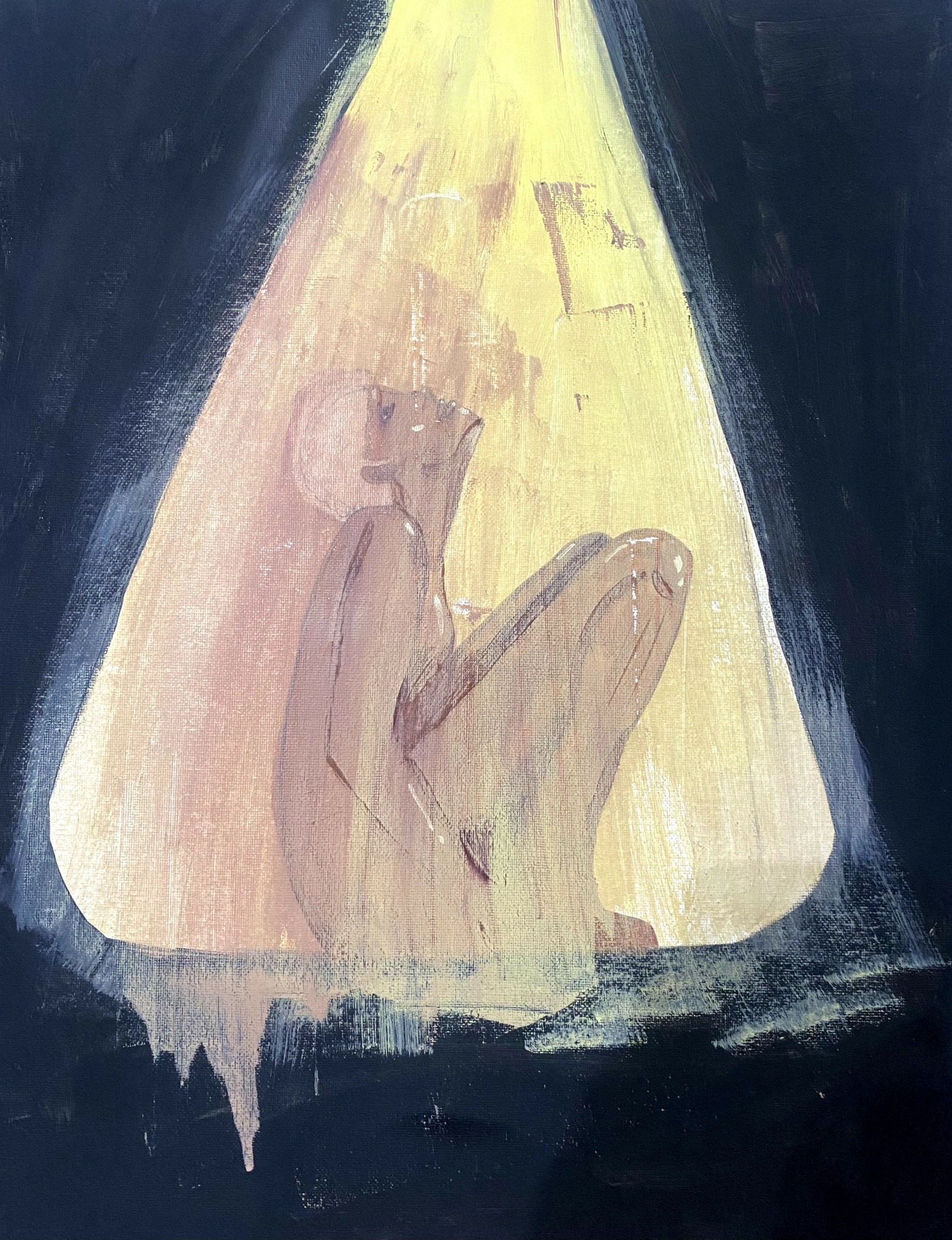 A person sitting with knees drawn up, illuminated by a spotlight against a dark background.