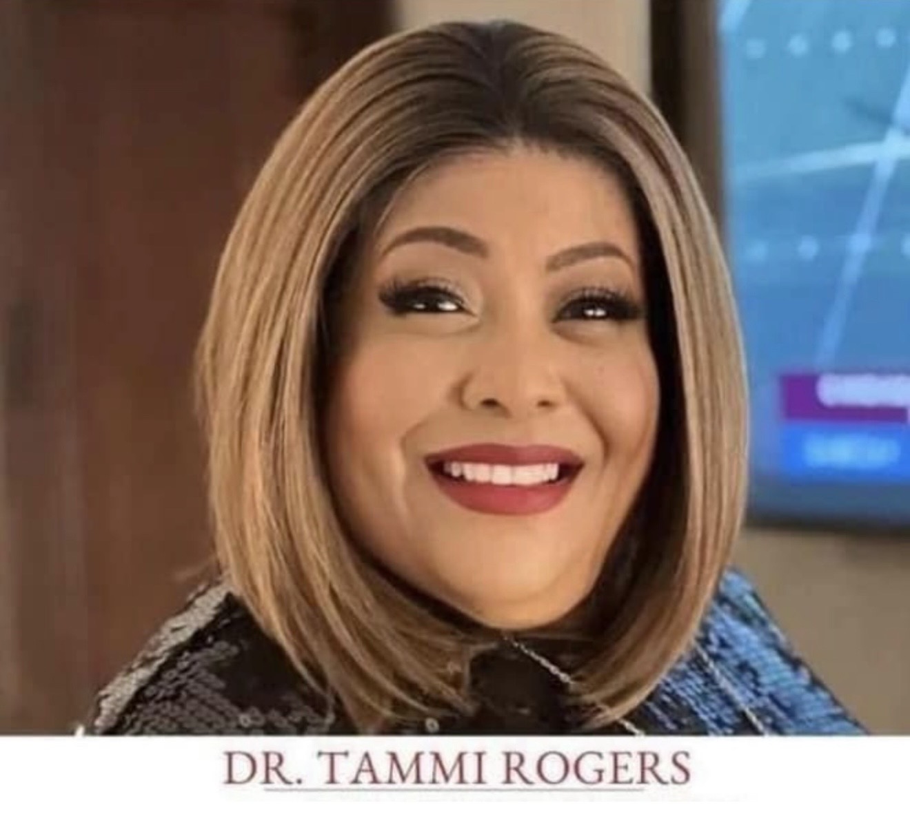 Woman with shoulder-length hair smiling, wearing makeup and a dark top, in front of a blue screen. Text: DR. TAMMI ROGERS.