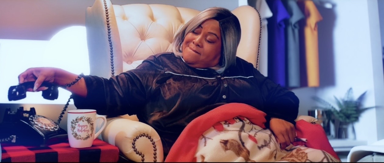 Woman relaxing in a chair with a drink and remote, eyes closed, in a cozy room.