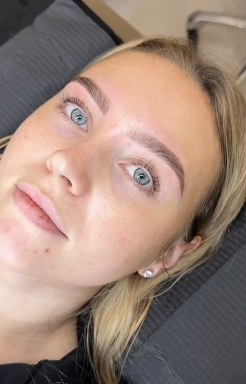 Close-up of a woman with blue eyes and blonde hair lying down, looking at the camera.