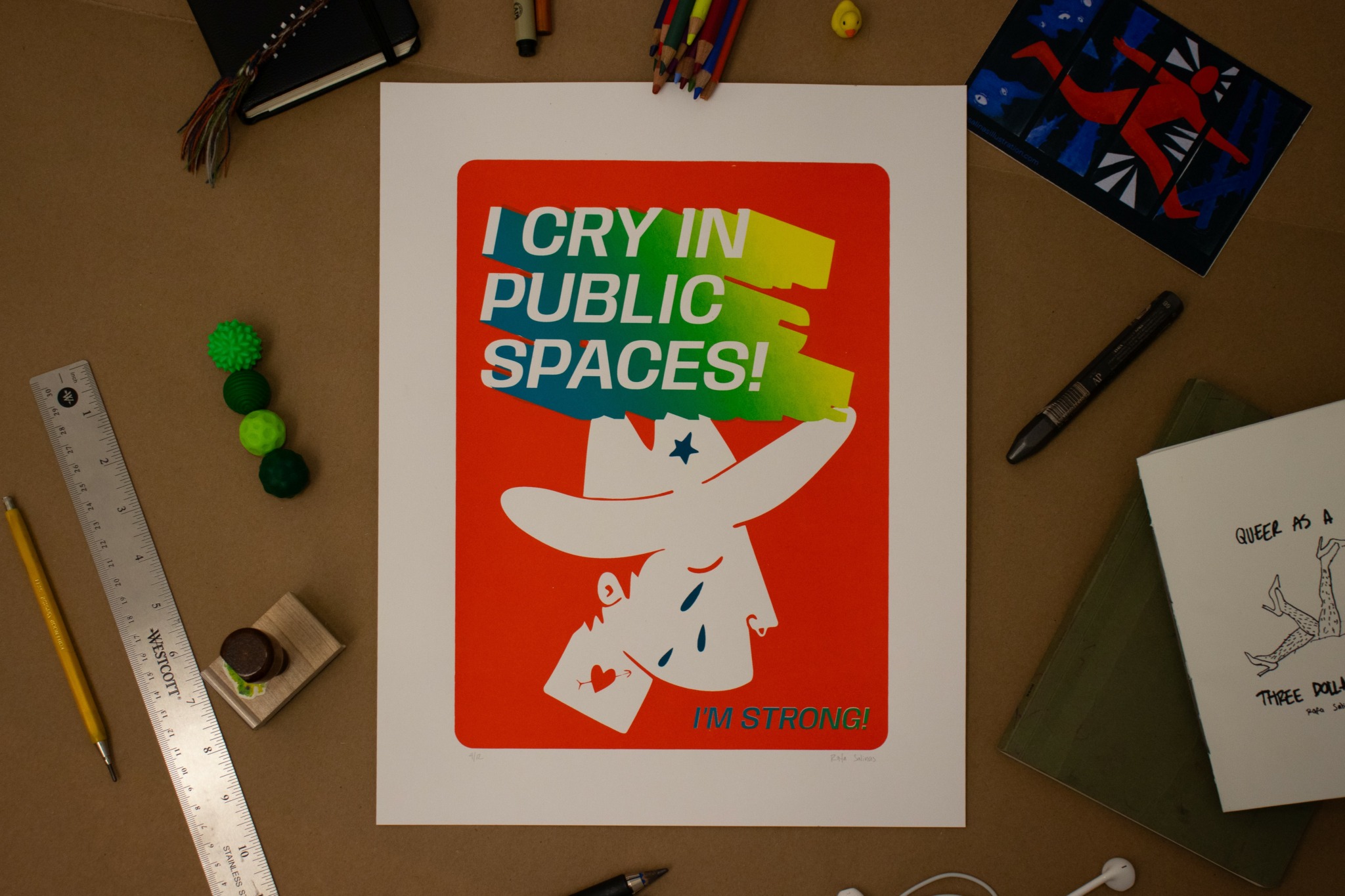Poster with colorful text and a white cartoon character on a red background, surrounded by art supplies and books.