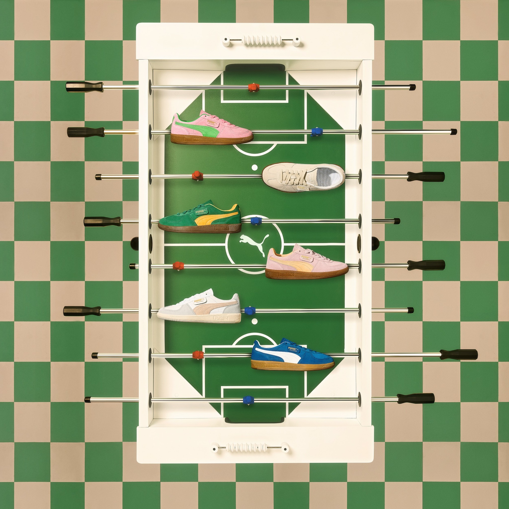 Foosball table with colorful shoes on the playing field, green and beige checkered background, and black handles.