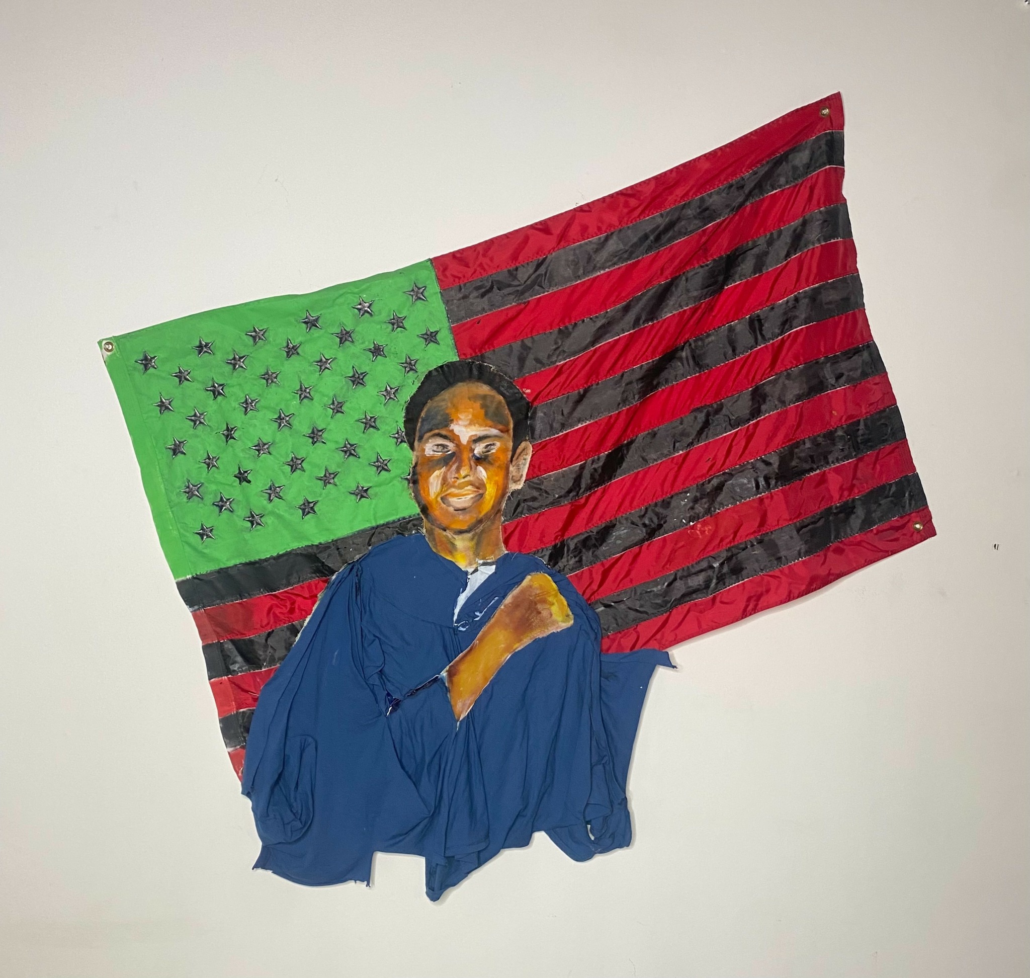 Fabric artwork of a person in blue clothing with a smiling face, in front of a green and red striped background.