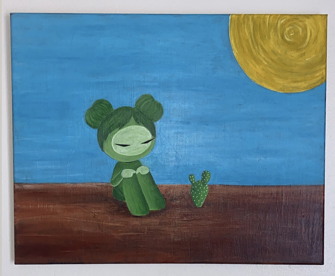 A green cartoon character with buns sits on brown ground under a blue sky with a yellow sun, next to a cactus.