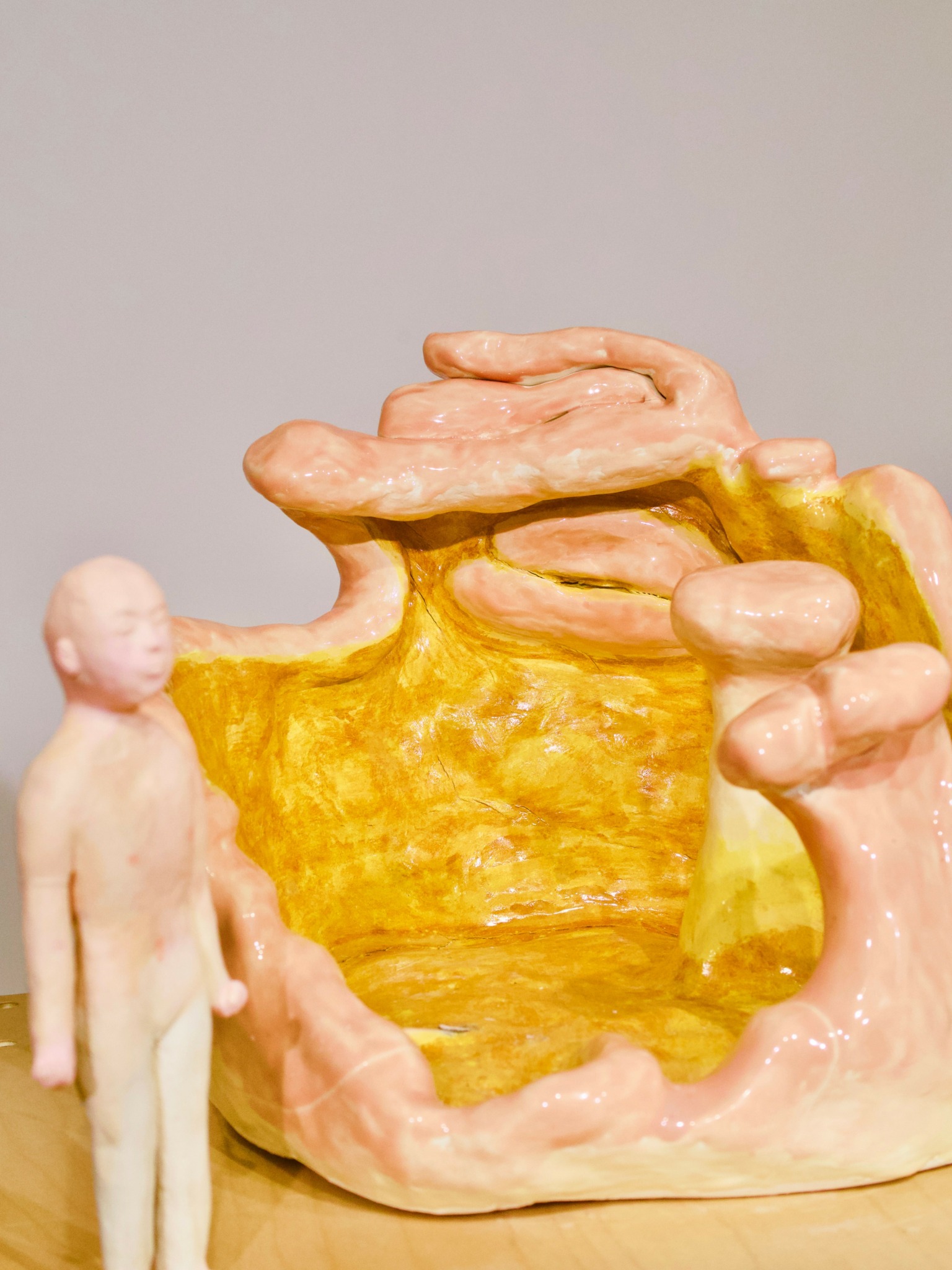 A sculpture of a child standing next to a large, abstract, multi-colored structure with pink, yellow, and beige elements.