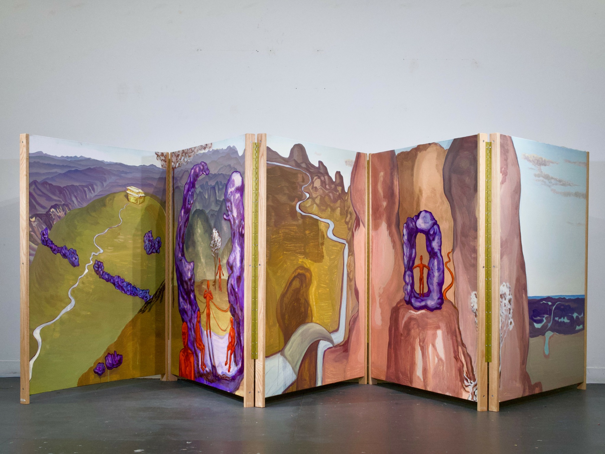 Open book with colorful landscape and abstract illustrations, standing upright on a gray surface against a plain white background.