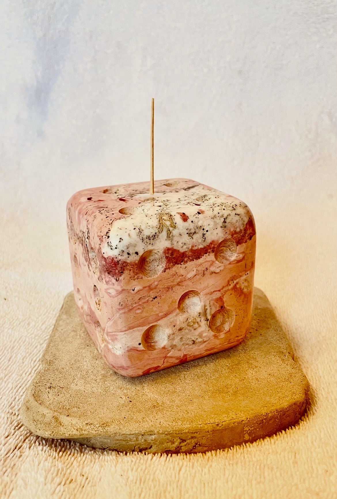 Square soap with bubbles on top, placed on a wooden surface, with a plain background.